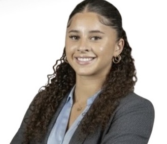 A woman in a business suit with curly hair, presenting a polished and professional appearance.