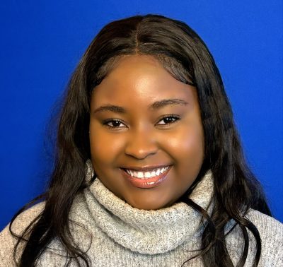 A young woman with a bright smile, dressed in a cozy turtleneck sweater, radiating positivity.